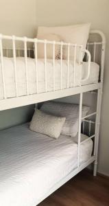 亚勒旺加Spacious Unit in Convenient Location的白色双层床,配有白色床单和枕头