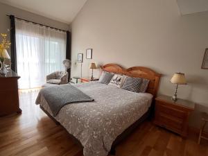 蒙特朗布朗Cozy 2 bedrooms condo with stunning Mont Tremblant mountain and lakeview的卧室配有床、椅子和窗户。