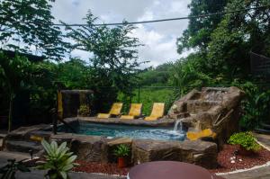 奎波斯城The Jungle Container的庭院内一个带椅子和瀑布的游泳池