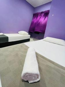 万挠FREE Wi-fi 100mbps I Emerald Cove Rawang的紫色客房的两张床,地板上配有一条毛巾