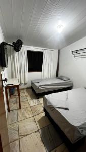 维多利亚Sossai Hostel的客房设有两张床、一张桌子和一台电视机。