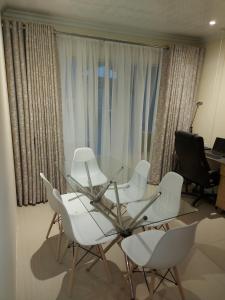 比勒陀利亚紫橄榄宾馆的一间设有玻璃桌和白色椅子的房间