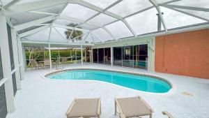 那不勒斯Paradise Naples Pool House的一个带两把椅子的玻璃屋顶下的游泳池