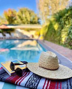 Upper Lake托尔曼酒店 的坐在游泳池旁毛巾上的草帽和太阳镜
