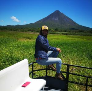 PalmaCasas de Campo Las Pavitas Cottages "Red Frog"的坐在一辆卡车后面的一位妇女,在车底下有山