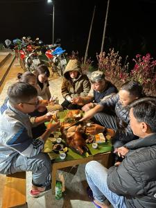 Quản BạHoàng nam Homestay的一群人坐在桌子旁,拿着火鸡