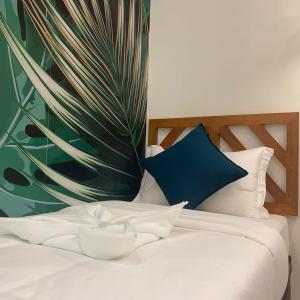 卢纳将军城Bahandi Hotel的一张带蓝色枕头和植物的白色床