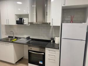 鲁维Apartamento Centro的厨房配有白色橱柜和白色冰箱。