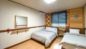 束草市Smile Resort的一间卧室设有两张床,墙上设有一面镜子