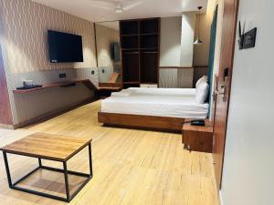 BrahmapurV HOTEL的一间卧室配有一张床、一张桌子和一台电视。