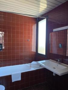 布鲁奇Hotel Bruc的红色瓷砖浴室设有浴缸和水槽