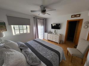 圣胡安海滩Casa Mariposa Guesthouse的一间卧室配有一张床、一台电视和一把椅子