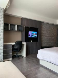 科贾扬Vins Room at Mataram City Tower Sadewa的酒店客房配有一张床、一张书桌和一台电视。
