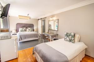 布隆方丹Glenmore Guesthouse的一间卧室配有两张床、一张桌子和一张桌子