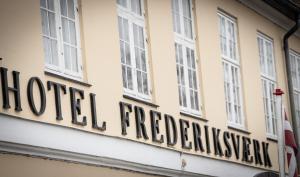 弗雷德里克斯伐克Frederiksværk Hotel的建筑一侧的标志,带有窗户