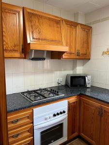 皮莱斯Casa playa Piles的厨房配有木制橱柜和白色炉灶烤箱。