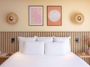 尼斯尼斯城中心圣母院美居酒店的卧室配有一张白色床,墙上挂有三张照片