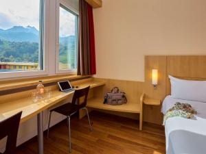 卢塞恩卢塞恩克林斯宜必思酒店的酒店客房设有一张桌子、一张床和一个窗户。