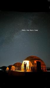 瓦迪拉姆Wadi Rum Mars Camp的站在星空下的圆顶前的几个人