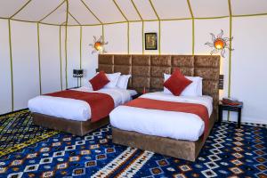 梅尔祖卡Yakout Merzouga Luxury Camp的带帐篷的客房内的两张床