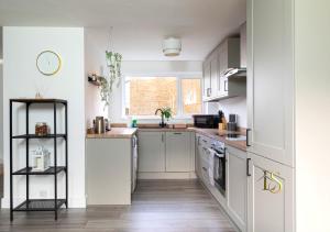 LemingtonLuke Stays - Hareydene的厨房铺有木地板,配有白色橱柜。