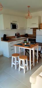 卢恰纳L'albizia Studio calme et tout confort的厨房配有白色橱柜、桌子和凳子