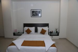 舍地塞班西酒店的卧室配有一张带白色床单和枕头的大床。