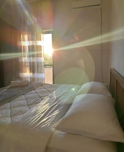 RinasHostel Rinas的卧室里的一张床铺,透过窗户阳光照耀