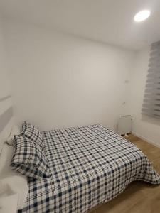 马德里Encantador apartamento completo con dos habitaciones的一张带 ⁇ 子毯子和两个枕头的床