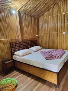 DāngchuraMoupiya Resort and Restaurant的木制客房内的一间卧室,配有一张床