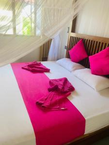 阿鲁特伽马Villa Riverside的一张带粉红色床单和粉红色浴袍的床
