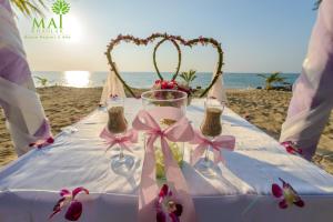 蔻立普吉岛-迈考海滩水疗度假村PL- Maikhaolak Beach Village的沙滩上的桌子,上面放着酒杯和鲜花