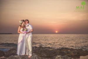 蔻立普吉岛-迈考海滩水疗度假村PL- Maikhaolak Beach Village的日落时分在海滩上新娘和新郎亲吻
