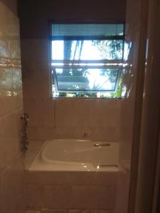 伯诺尼Blue Oasis Apartments的带浴缸的浴室和窗户