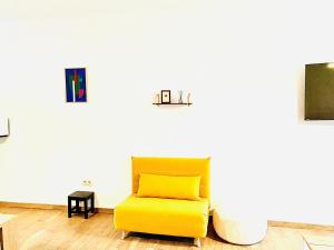 沙勒罗瓦Résidence Deluxe的白色墙壁的房间里一张黄色椅子