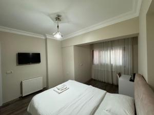 大切克梅杰Doğa Villa Guest House的卧室配有白色的床和平面电视。