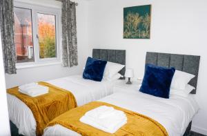 威根The Oasis的白色客房的两张床,配有蓝色枕头