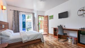 乌库拉斯Coco Villa Ukulhas的一间卧室配有一张床、一张书桌和一台电视