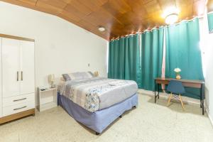 圣萨尔瓦多Volcano Hostal y Restaurante的一间卧室配有一张床、一张书桌和绿色窗帘