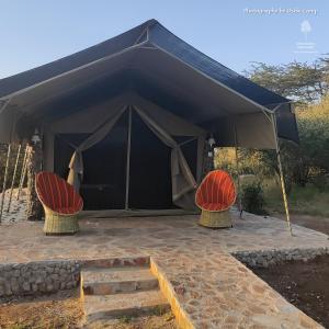NarokOseki Maasai Mara Camp的黑色帐篷下配有两把椅子