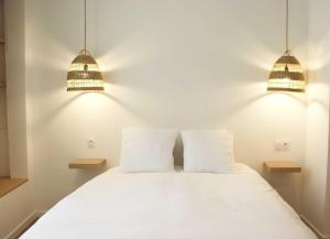 坦耶尔米塔格Charmant studio en plein coeur de Tain l'Hermitage的一间卧室配有两盏灯和一张白色的床。