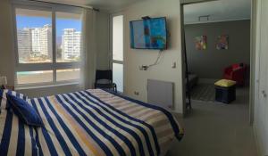拉塞雷纳Departamento La Serena Laguna del Mar的一间卧室配有一张带蓝白条纹毯子的床