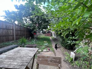 伦敦Relaxing&Cozy Room的一只黑猫在带木桌的花园中漫步