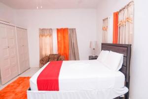 圣玛丽Suzette Guesthouse Accommodations的卧室配有白色的床和橙色窗帘