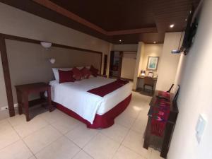 Santa Lucía Milpas AltasHOTEL Y RESTAURANTE HACIENDA LOS VOLCANES的卧室配有带红色枕头的大型白色床
