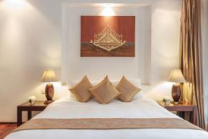 万象绿园精品酒店的卧室配有带枕头和两盏灯的白色床。