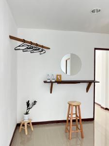 那空拍侬府ดวงใจโฮมเทล Duangjai Hometel的白色的墙壁,带镜子和两张凳子
