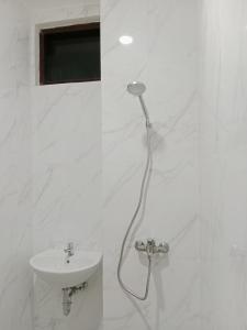 泗水Hotel Andita Syariah的带淋浴和盥洗盆的白色浴室