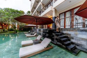 乌布Anumana Ubud Hotel的站在带遮阳伞的游泳池旁的人