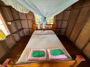 昌岛Changthong Bungalow的一张床位,房间配有两条绿色和粉红色的毛巾
